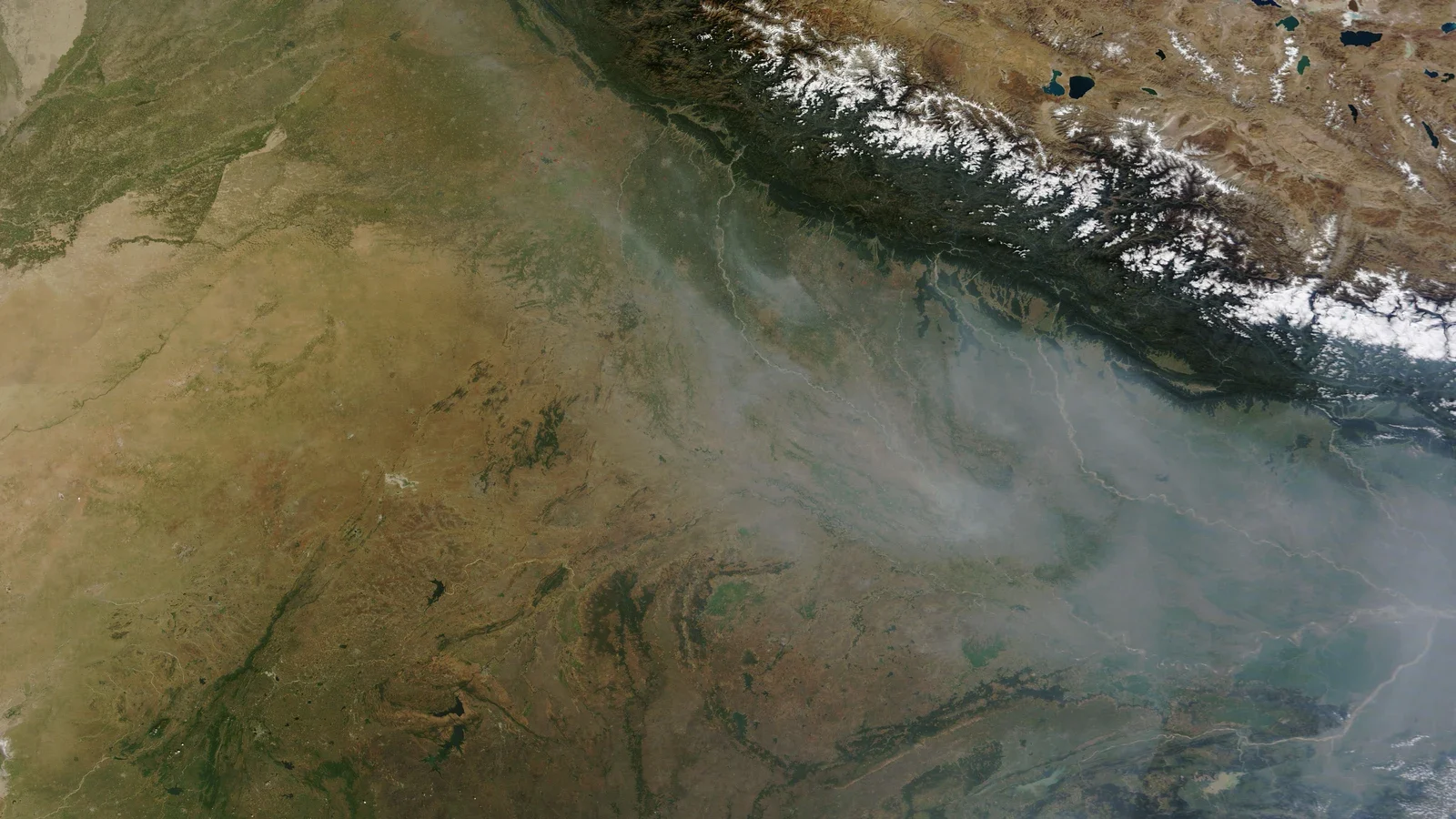 True-colour satellite image of northwest India showing grey haze lying across the plain along the base of the Himalaya.